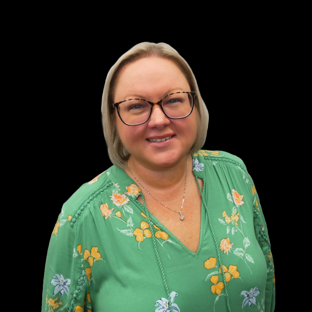 A woman wearing glasses and a green floral shirt is smiling.