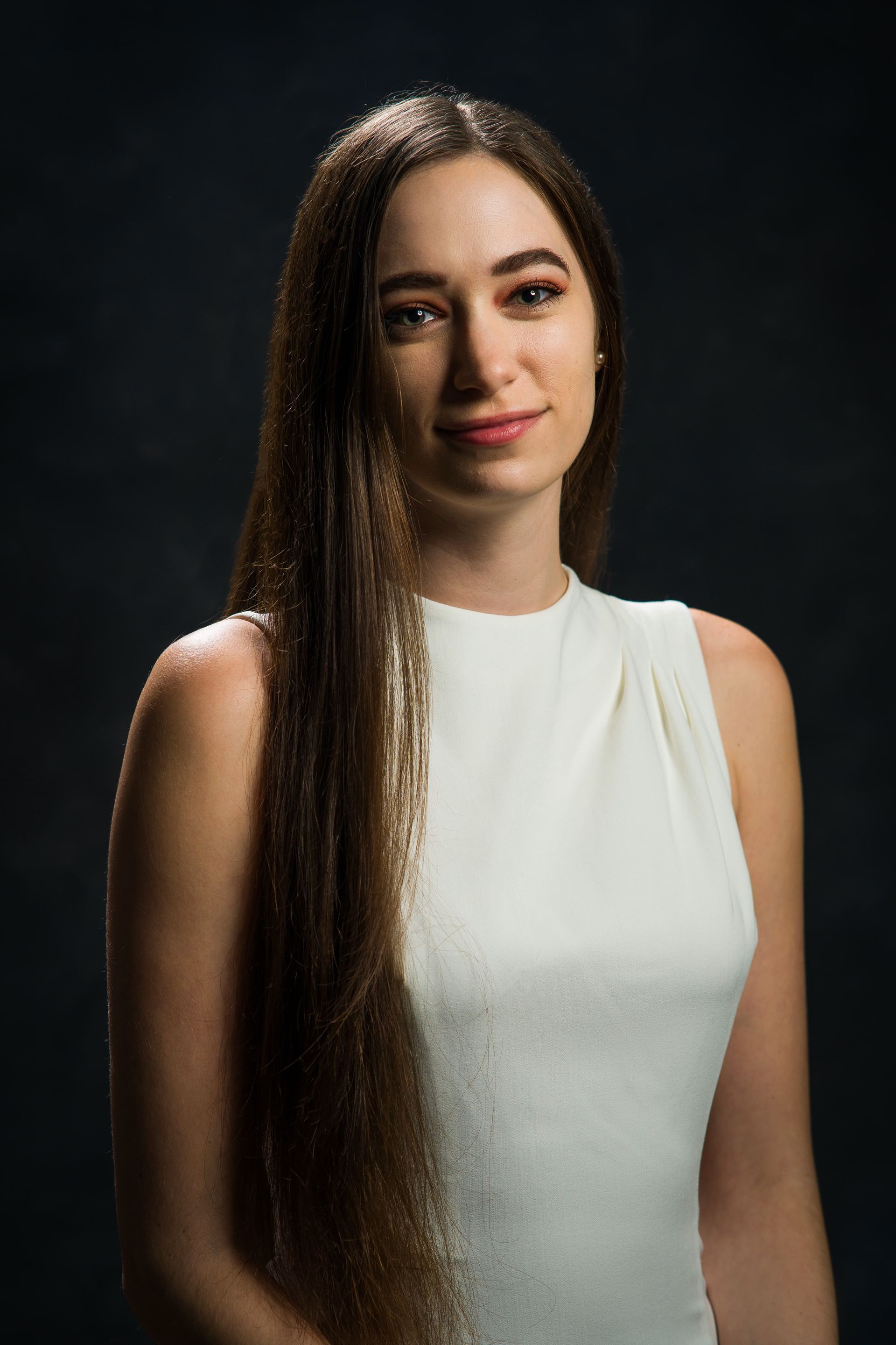 A woman with long hair is wearing a white tank top.