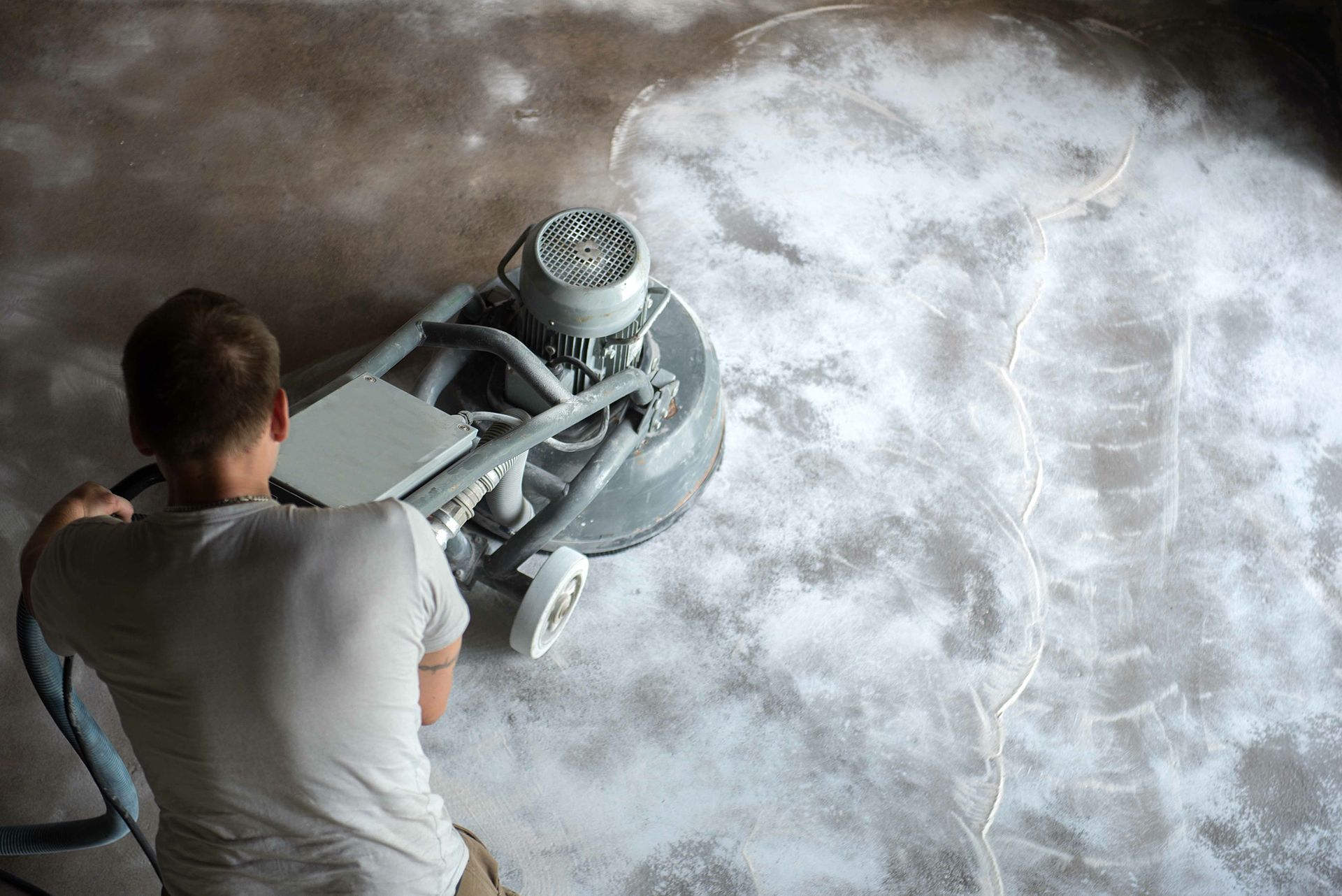 A man is grinding a concrete floor.