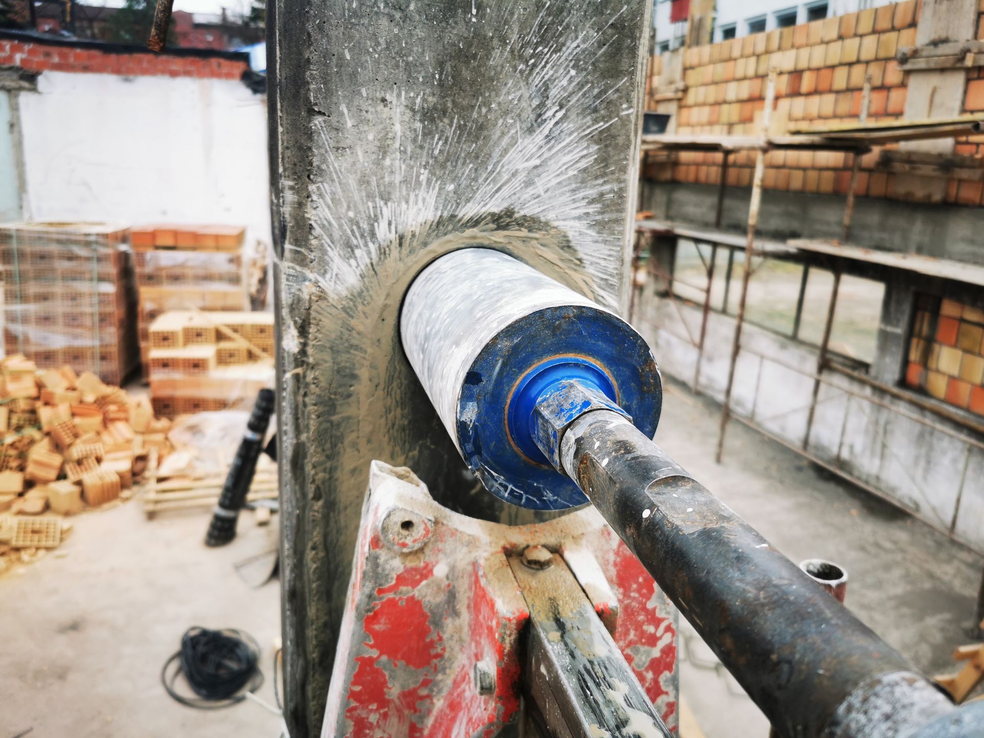 A hole cutting machine with an industrial diamond grain drilling a reinforced concrete column. A hole cutting machine with an industrial diamond grain drilling a reinforced concrete column.