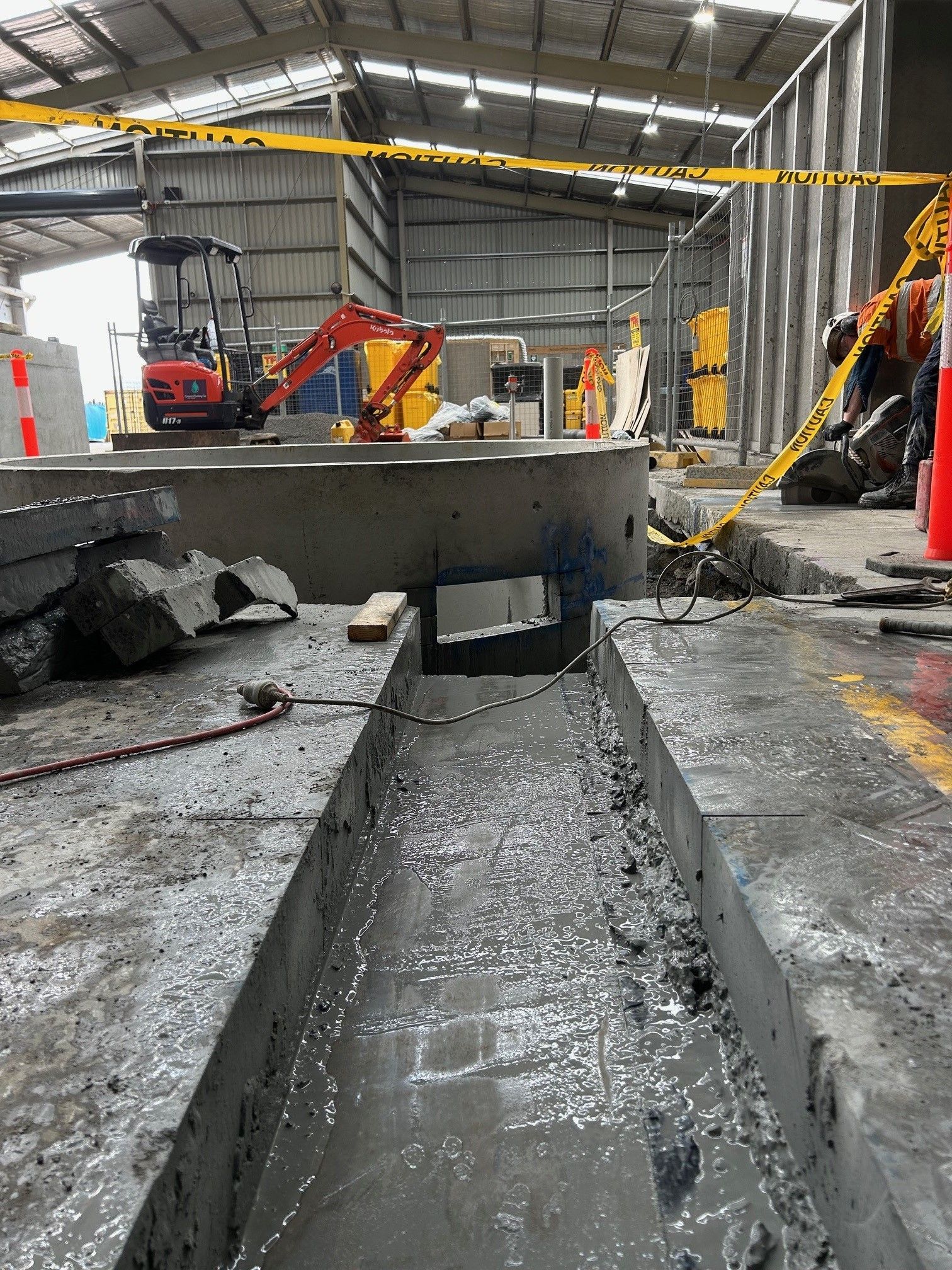 A large concrete slab is being cut in a warehouse.
