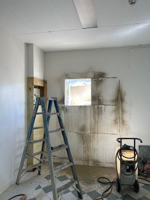 A room with a ladder and a vacuum cleaner in it.