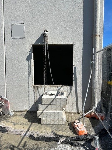 A hole in the side of a building is being filled with concrete