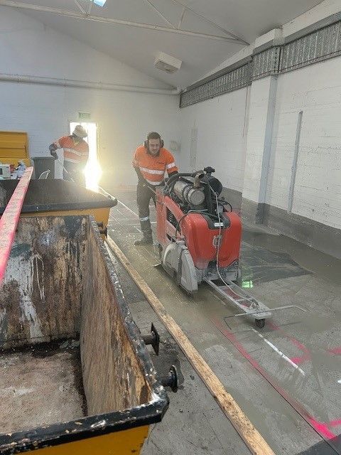 A man is using a machine to cut concrete in a building.