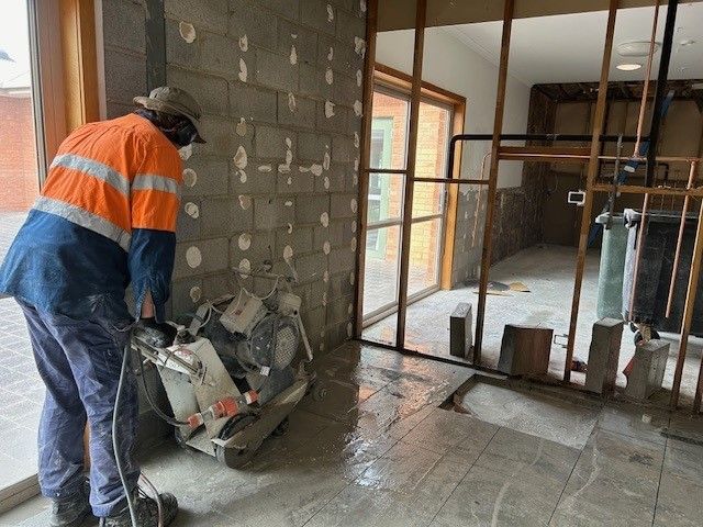 A man is cutting a hole in a wall with a saw.