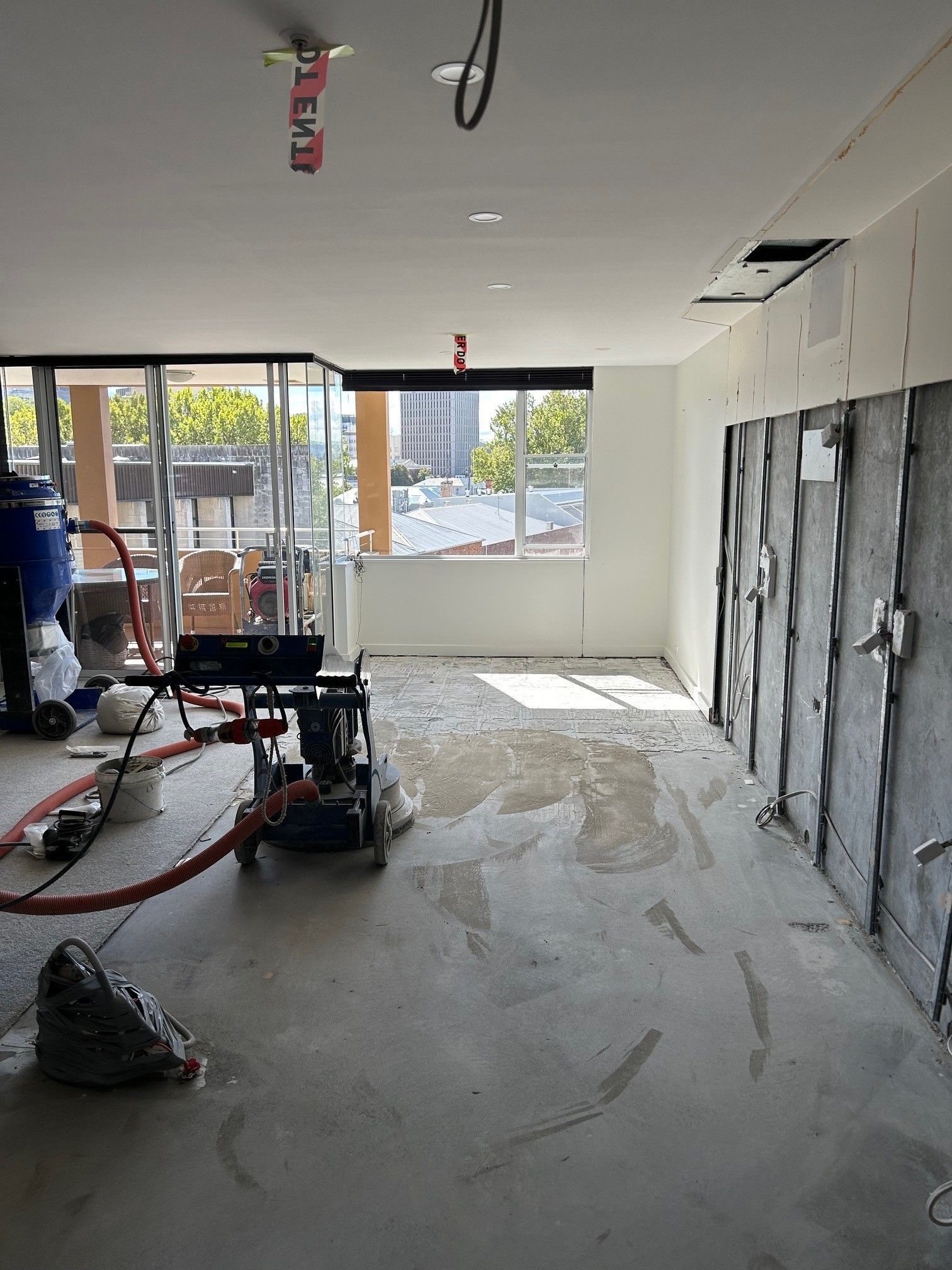 A large room with a lot of windows and a vacuum cleaner on the floor.