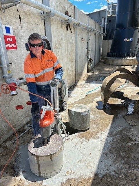 A man is using a machine to cut a hole in the ground