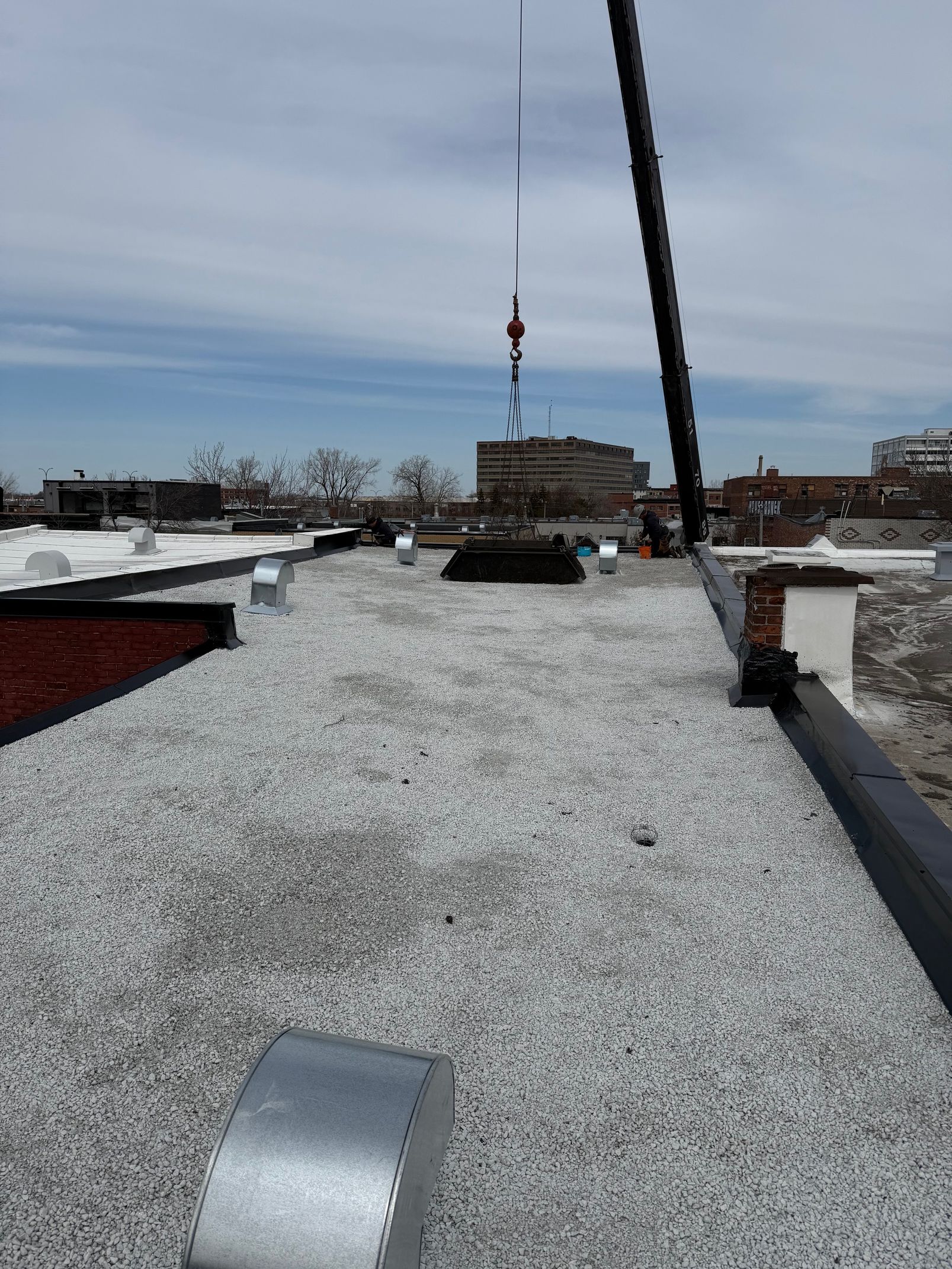 Une grue soulève un morceau de métal sur un toit.