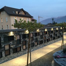 Un grand bâtiment avec un mur de pierre et des arbres devant.