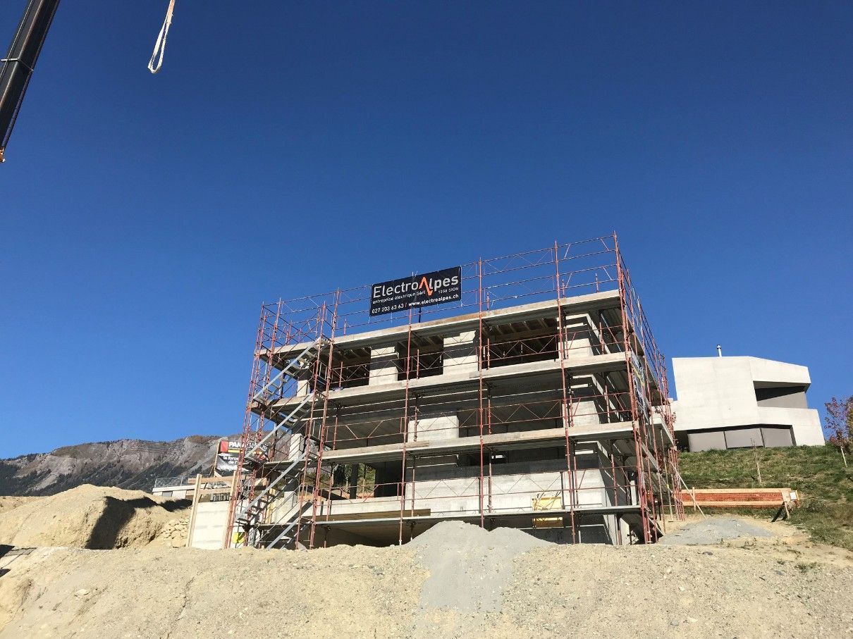 Un bâtiment en construction avec des échafaudages et une grue en arrière-plan.