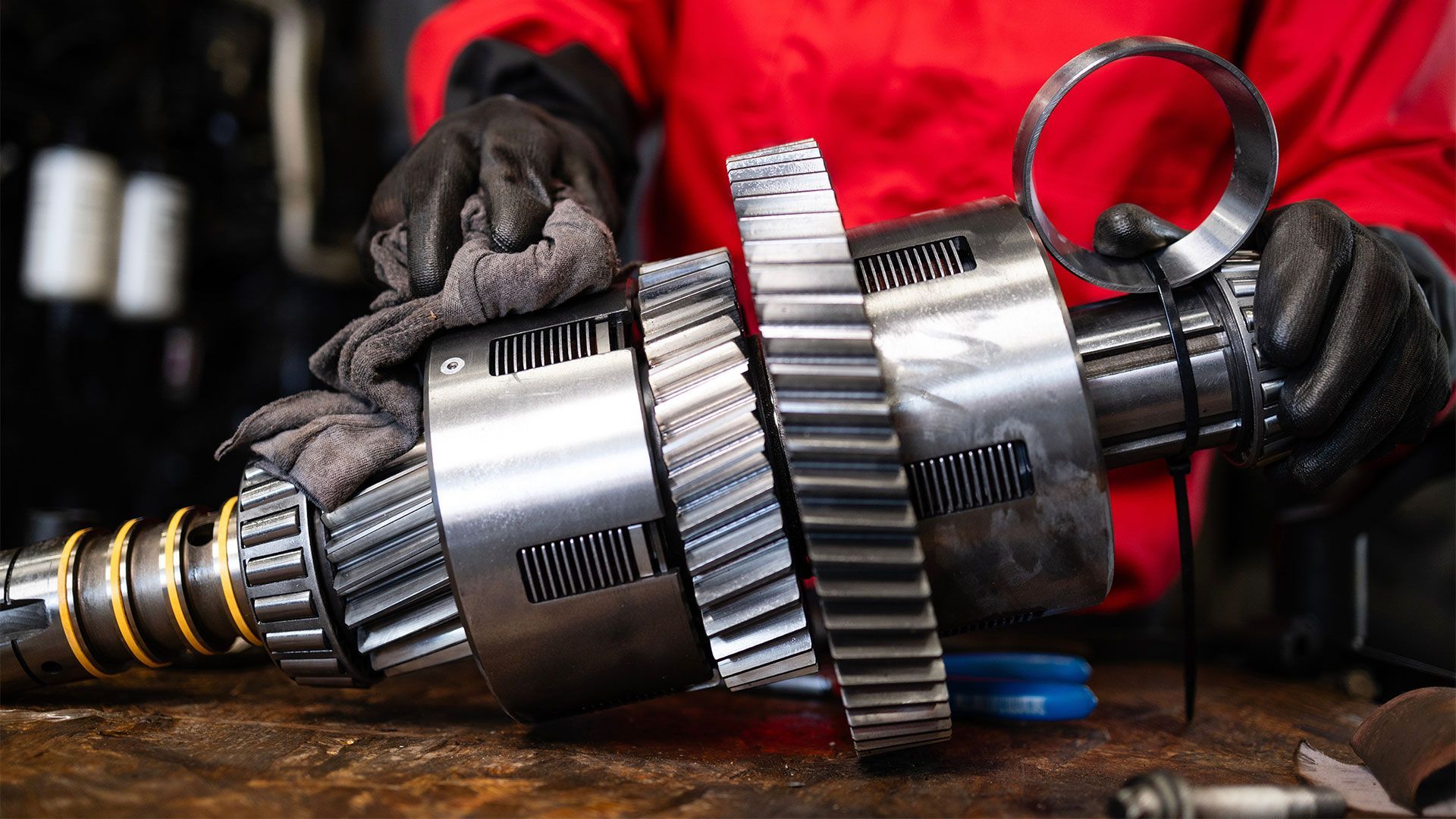 A person in a red shirt is working on a gear