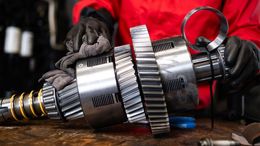 A person in a red shirt is working on a gear