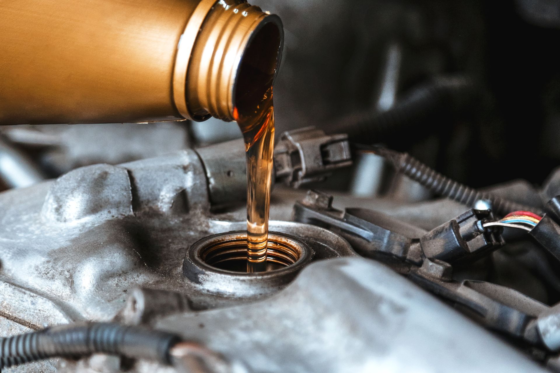 A close up of a person pouring oil into a car engine.