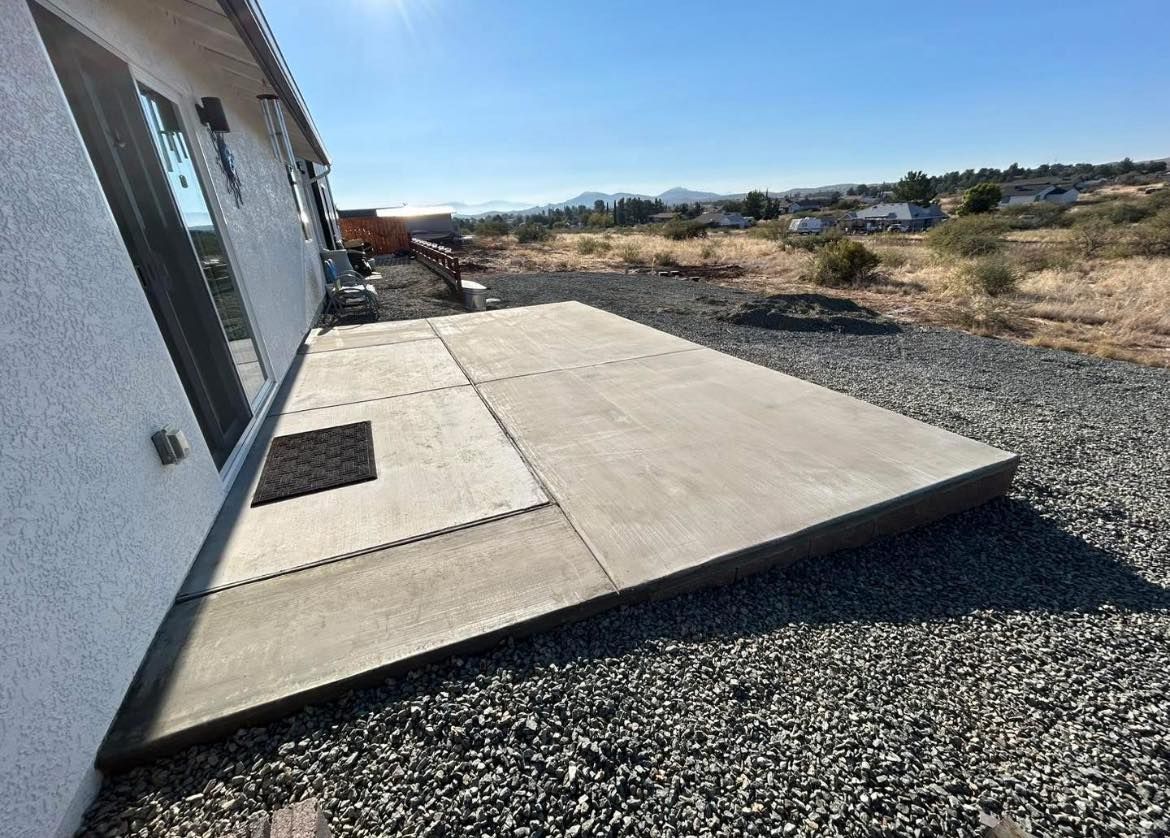 Concrete patio next to a house with a gravel yard.