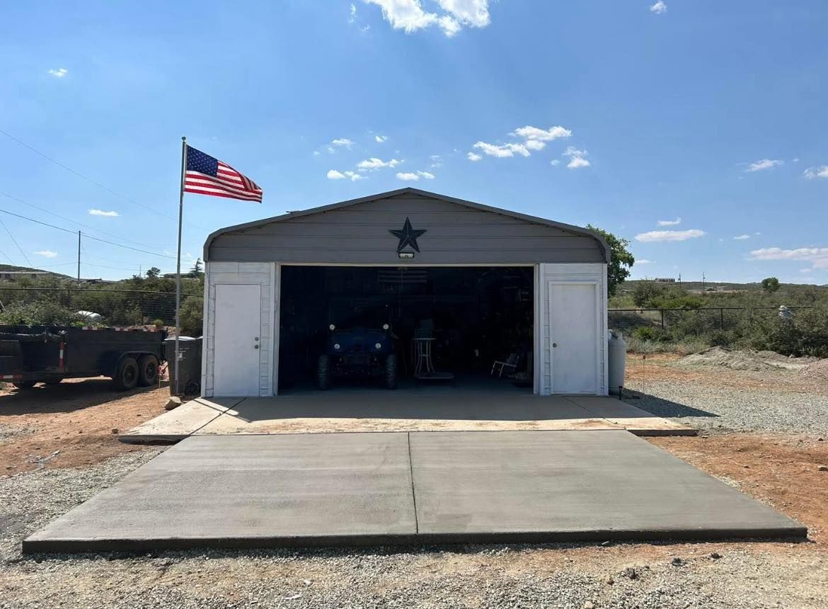 Garage with an American flag, open door, and concrete driveway on a sunny day.