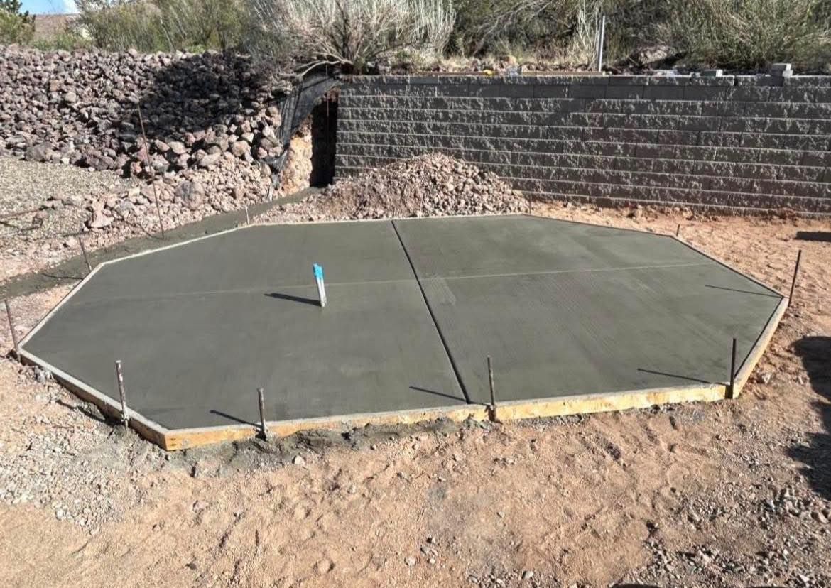 Freshly poured, octagonal concrete slab in a dry, rocky outdoor setting.