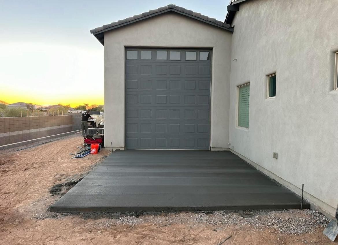 Freshly poured concrete driveway in front of a gray garage door.  Construction in progress.