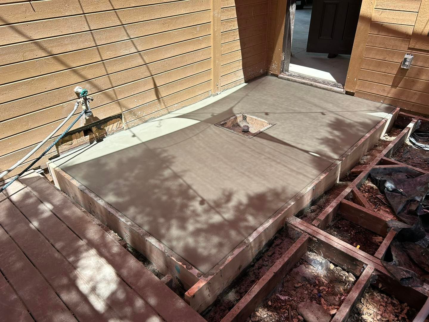 Construction site: concrete slabs for a deck, surrounded by exposed wooden framing and siding.