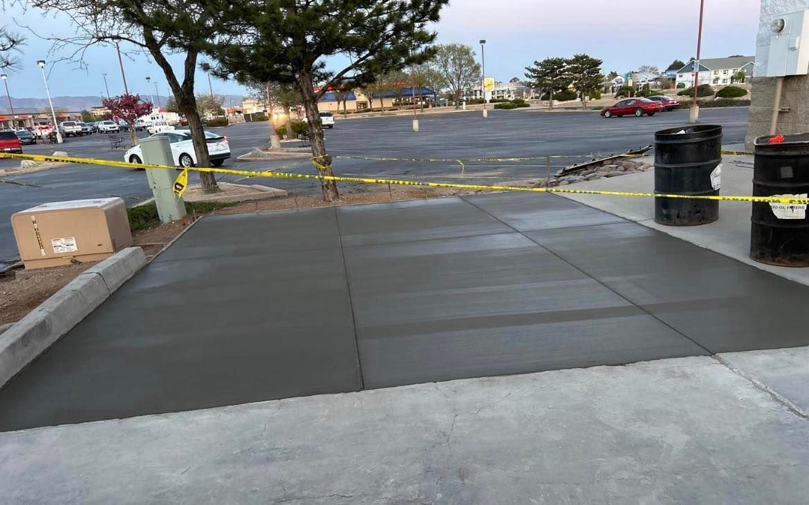 Freshly poured concrete slabs in front of a parking lot, marked off with yellow caution tape.