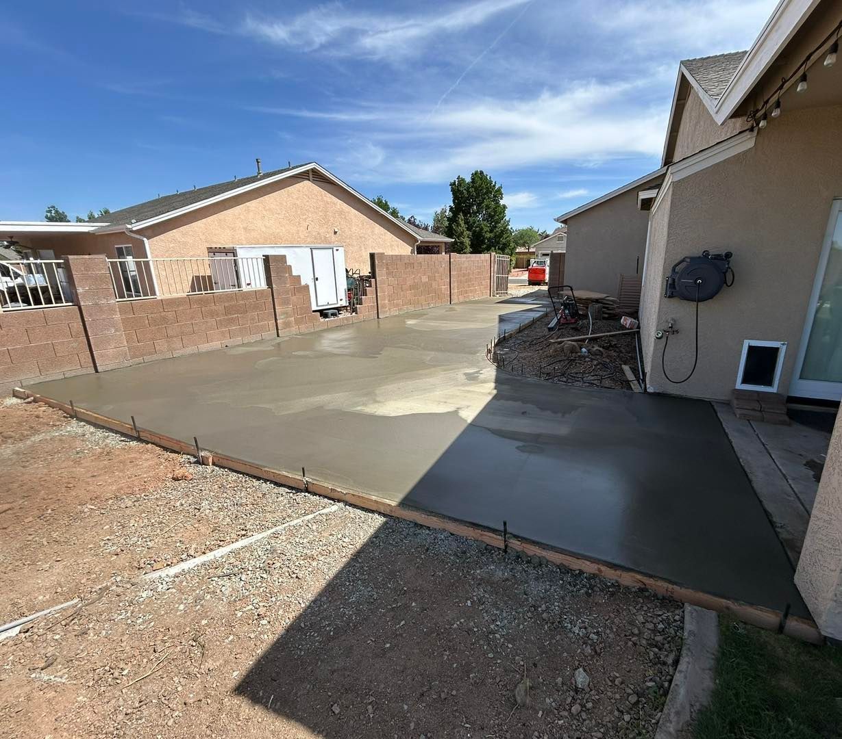 Freshly poured concrete patio in a backyard setting.