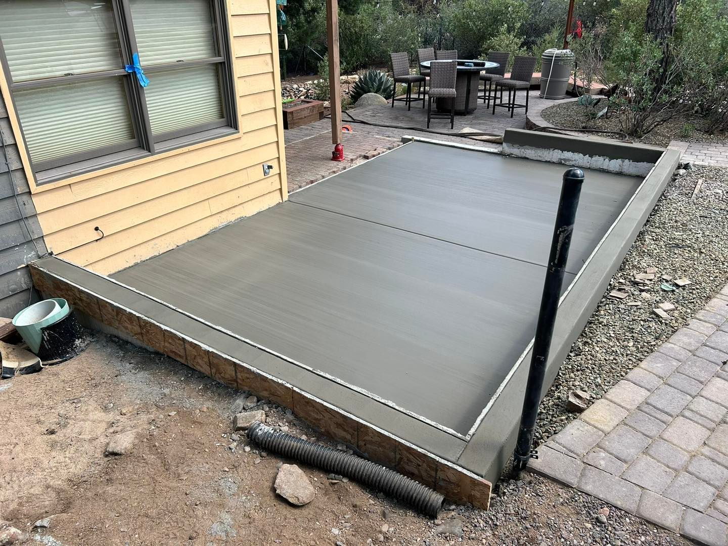 Freshly poured concrete patio with wood formwork, next to a building.