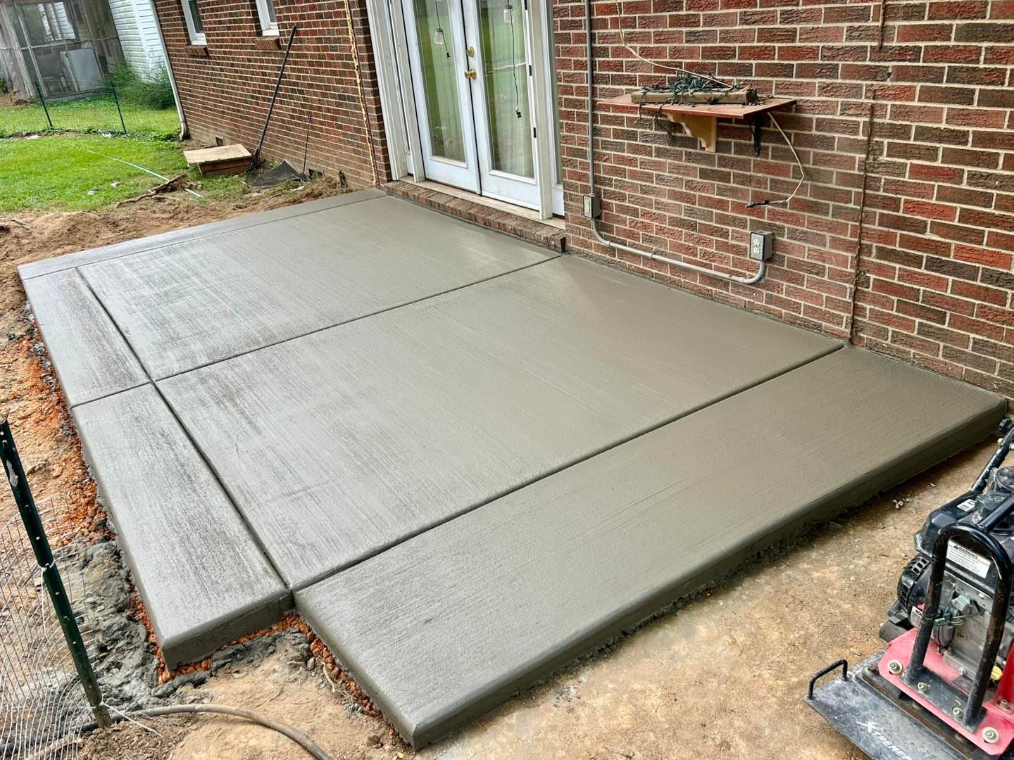 Newly poured concrete patio next to a brick building.
