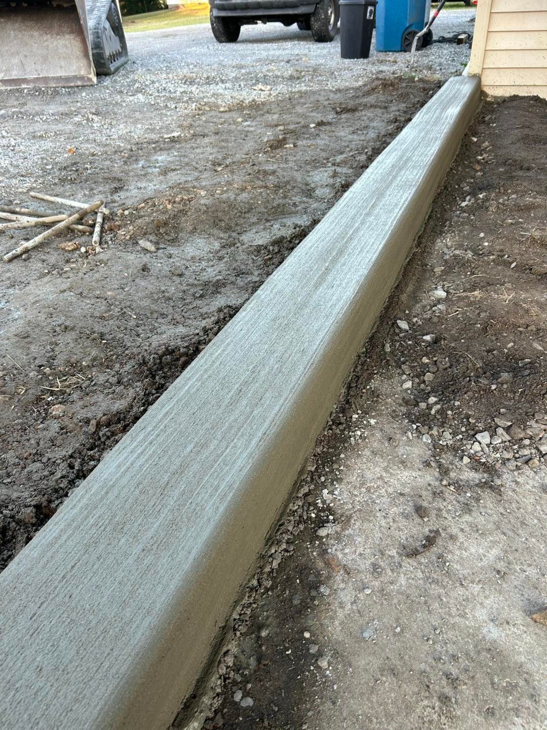 Freshly poured concrete curb along a driveway.