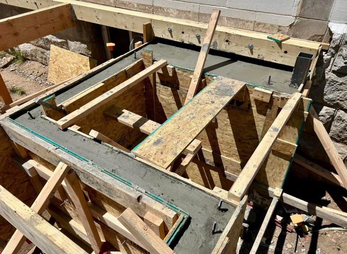 Wooden forms filled with wet concrete, part of a construction project outdoors.