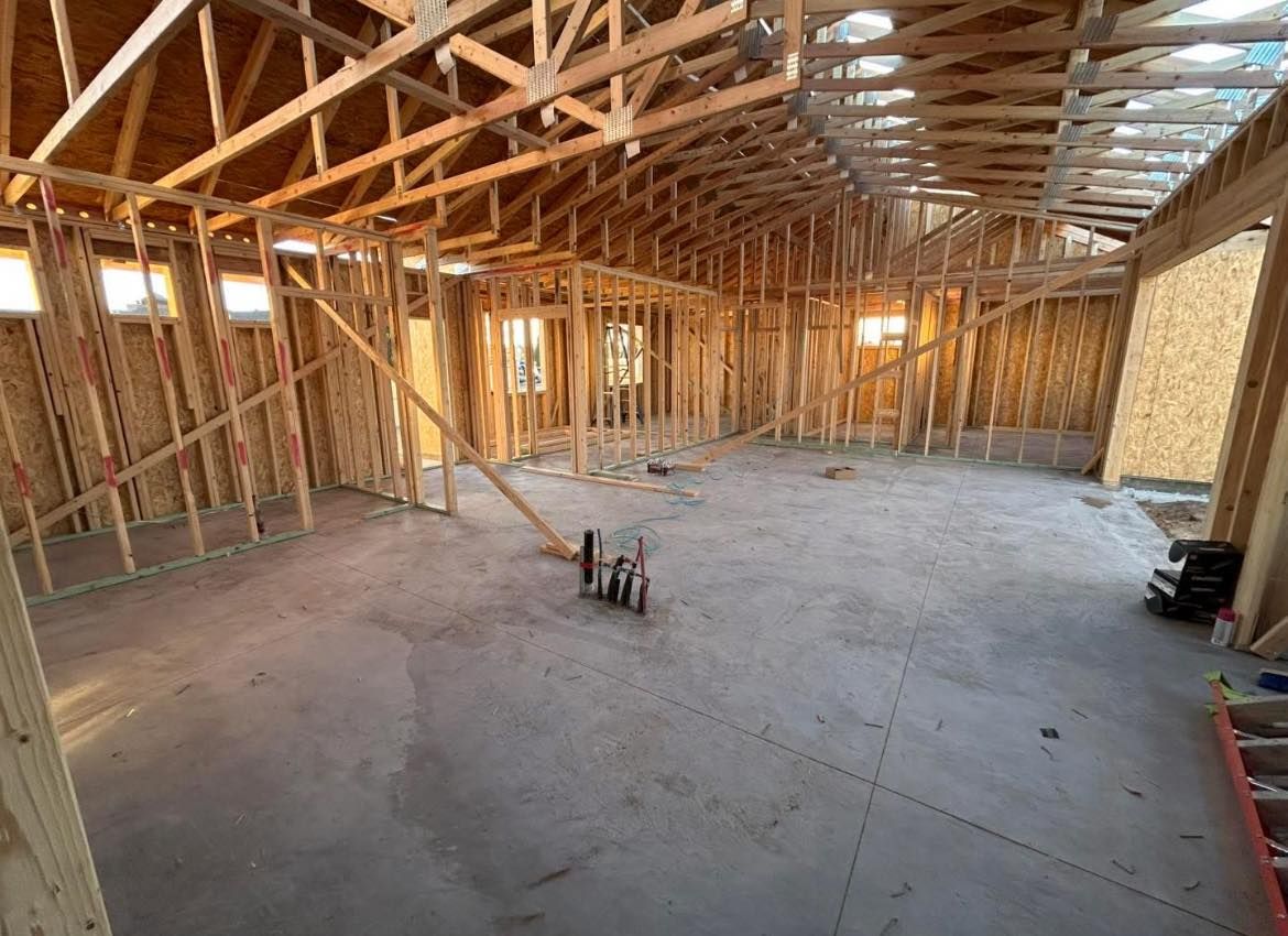 Interior of a building under construction, showing wooden framework and concrete floor.