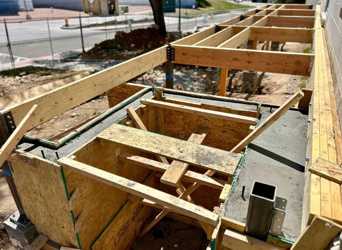 Construction site with wooden framing for a deck. Concrete base and support beams visible.
