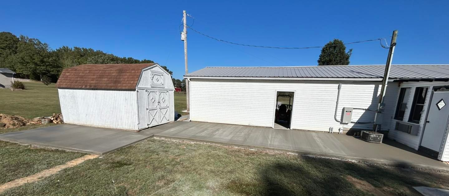 White buildings with shed and paved area on a sunny day.