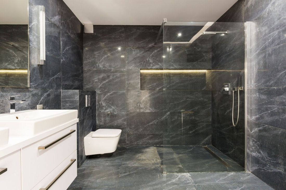 Bagno di design con pareti e piatto doccia in marmo