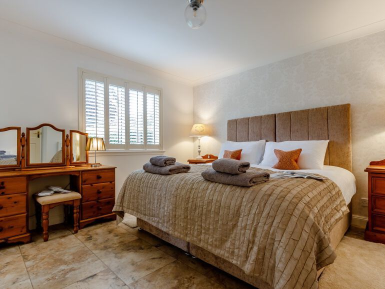 Super-king-size bed with folded towels and dressing table on one side