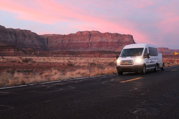 A white van with a trailer attached to it is driving down a road.