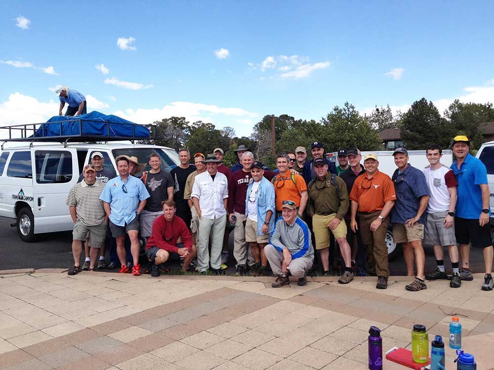 A group of men are posing for a picture in front of a van.