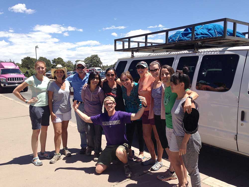 A group of people are posing for a picture in front of a van.