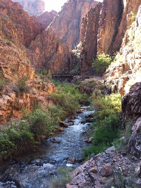 A river running through a canyon with a bridge in the background.