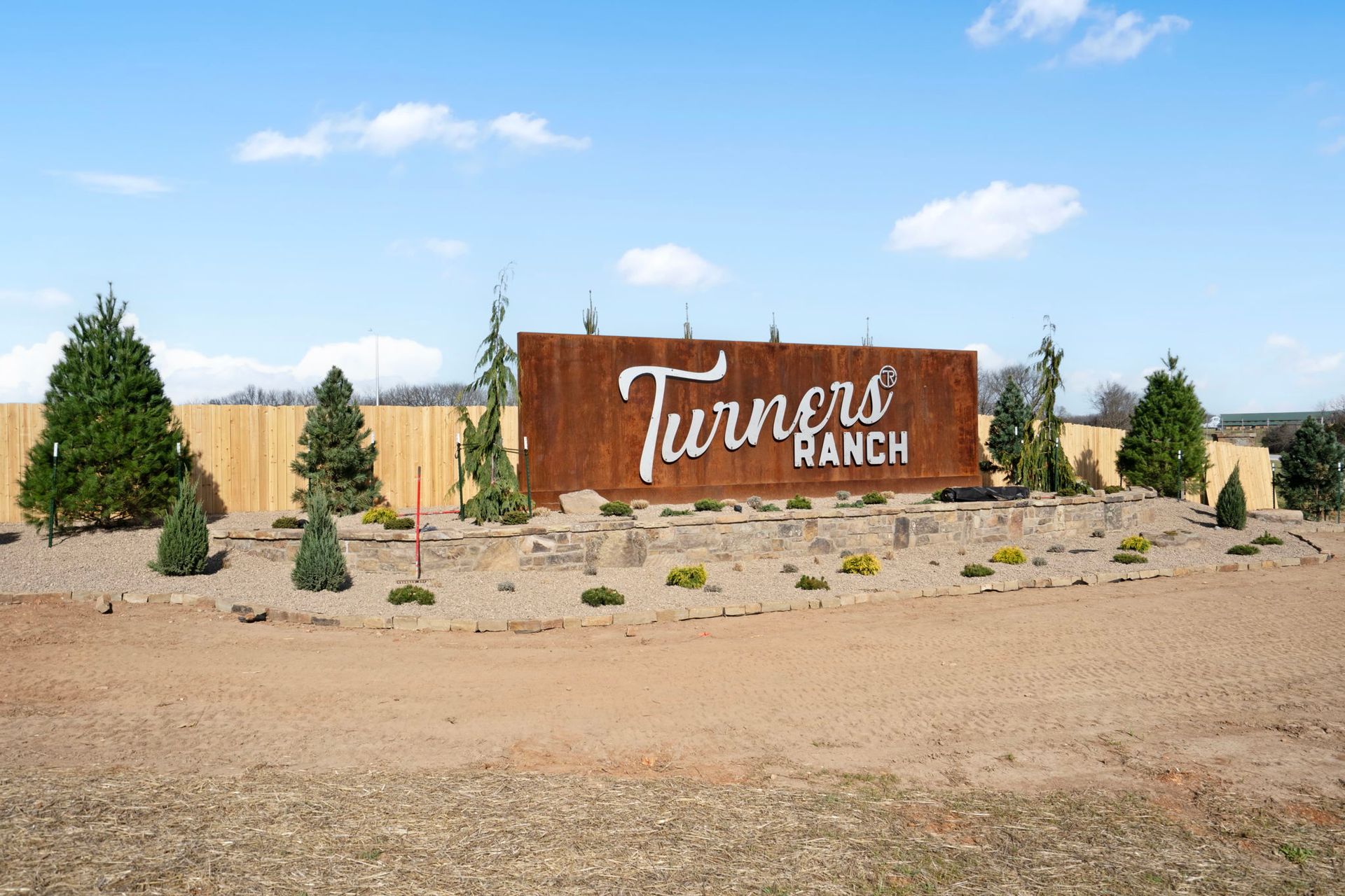 Aerial view of a community center with parking, pool, pickleball court, putting green, and surrounding trees.