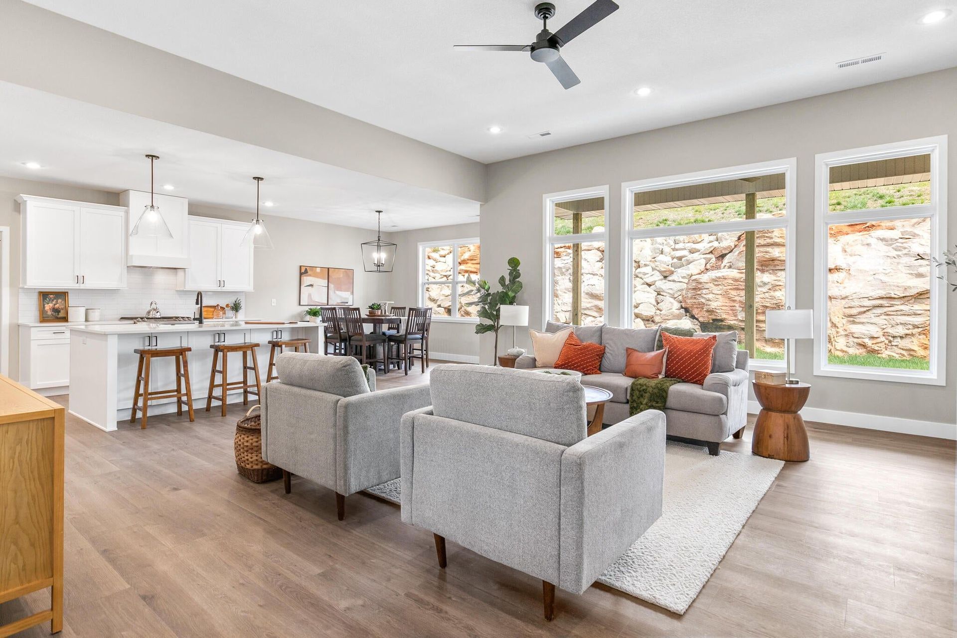 Open-concept living space with kitchen, dining, and living areas. Neutral colors, natural light, and modern furniture.