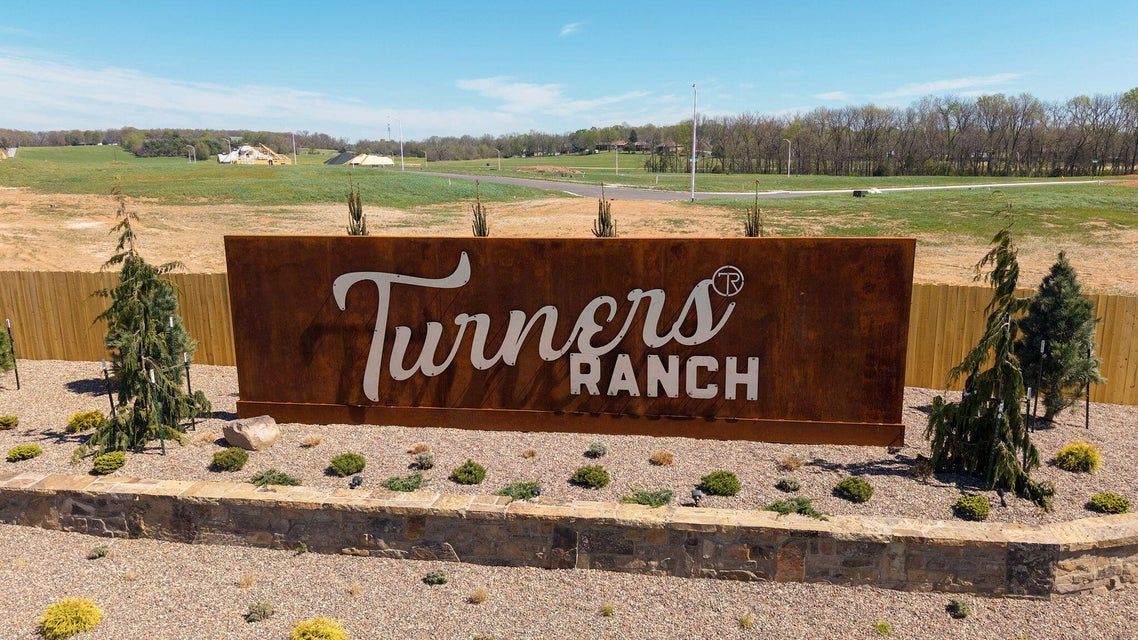 Swimming pool with stone building, people swimming and lounging on a sunny day.