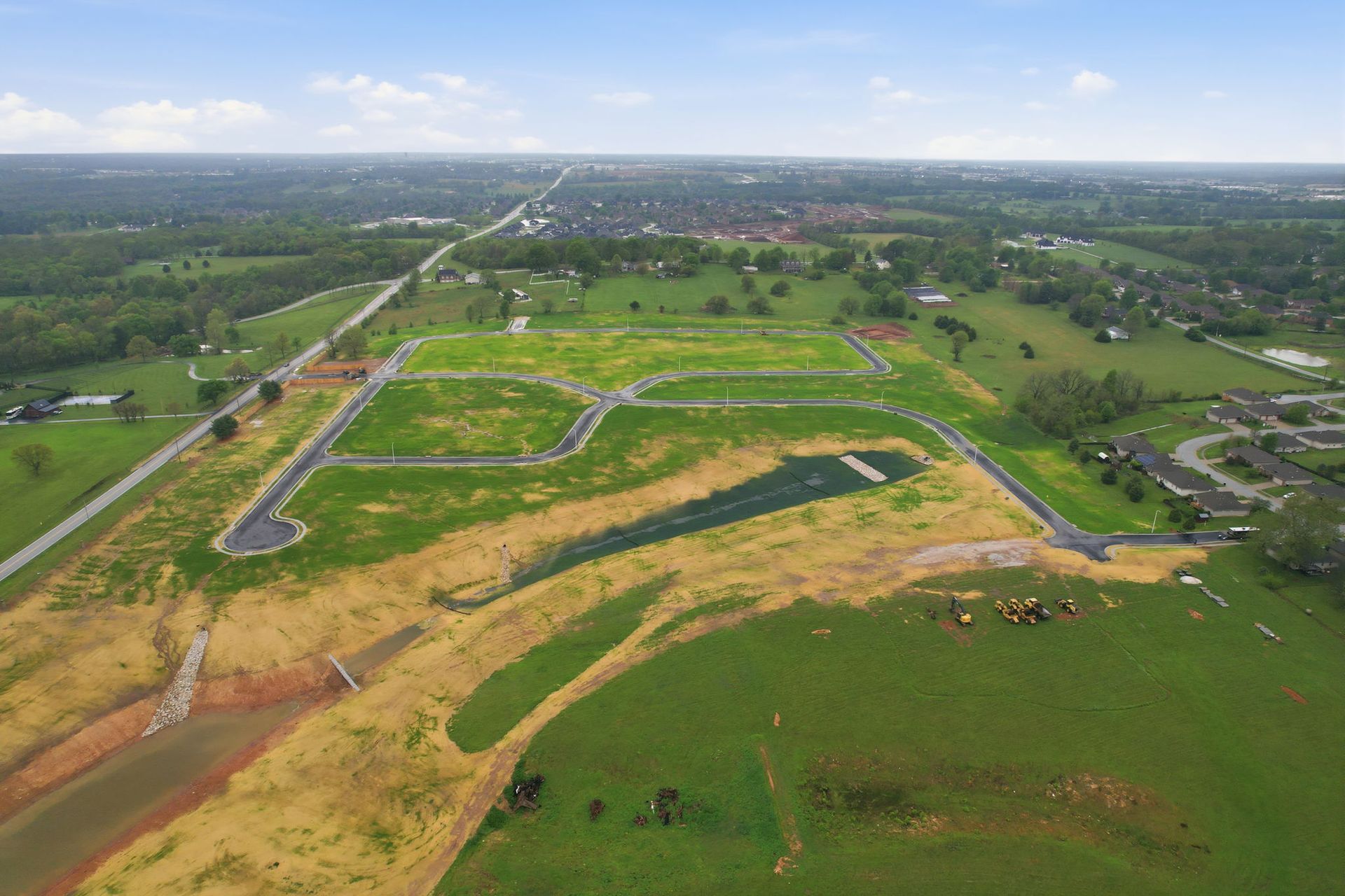 Aerial view of a community center with parking, pool, pickleball court, putting green, and surrounding trees.
