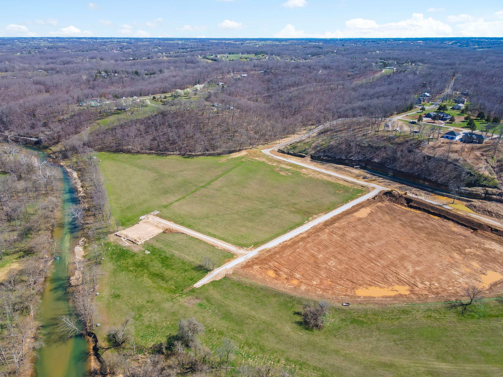 Sunset view from paved road overlooking bare trees in a neighborhood