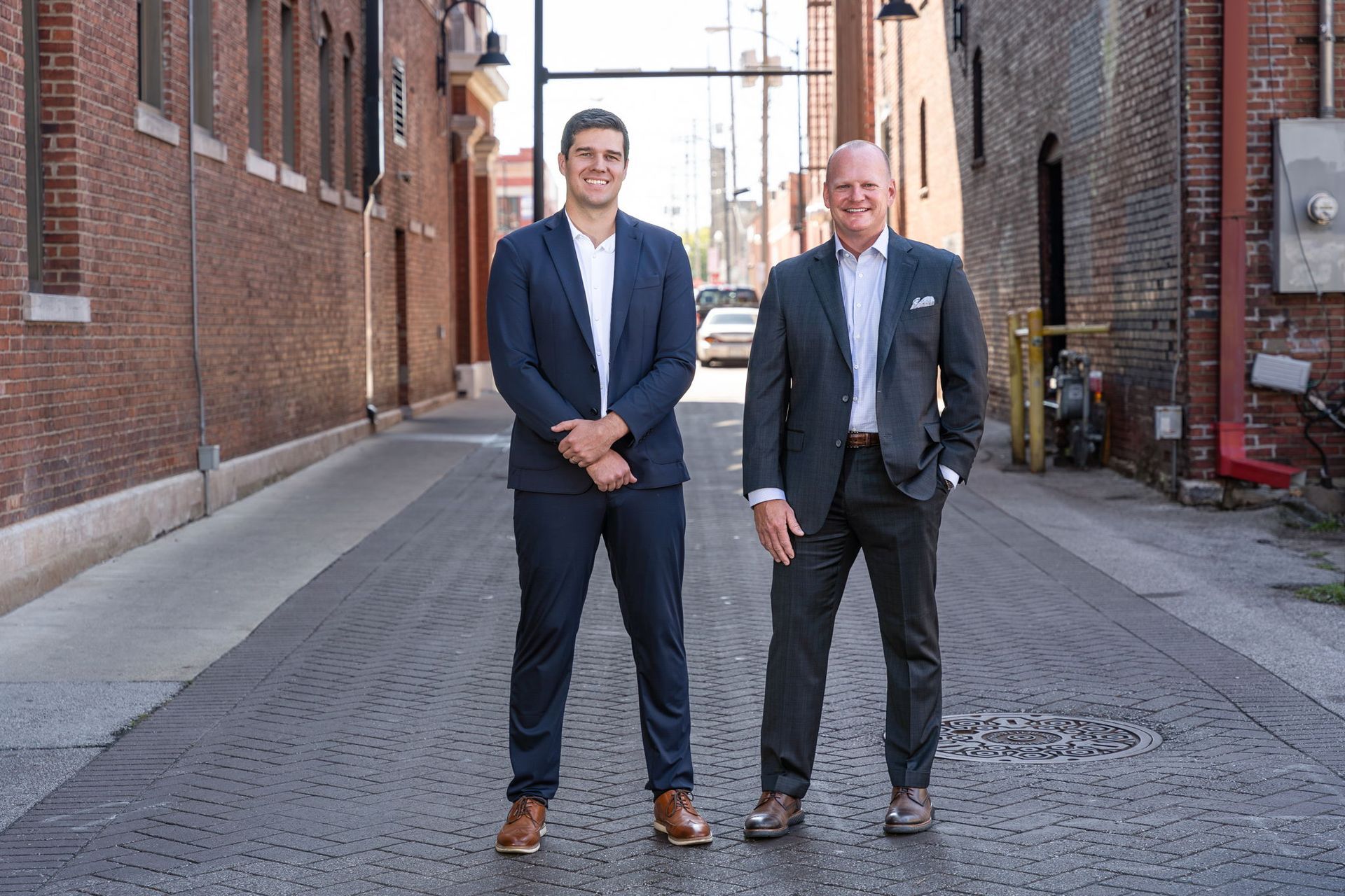 Keller Williams real estate office with red neon sign on a gray and black building with green grass.