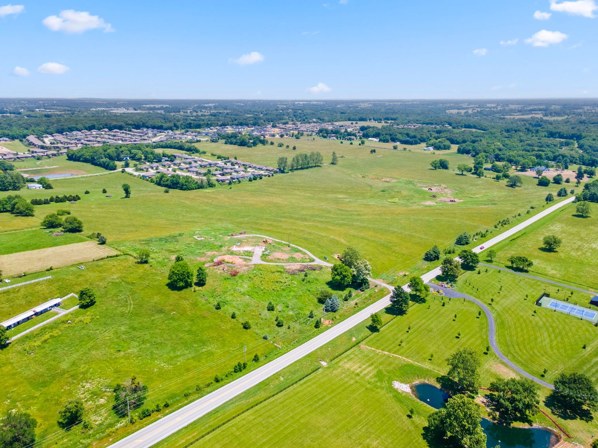 Swimming pool with stone building, people swimming and lounging on a sunny day.
