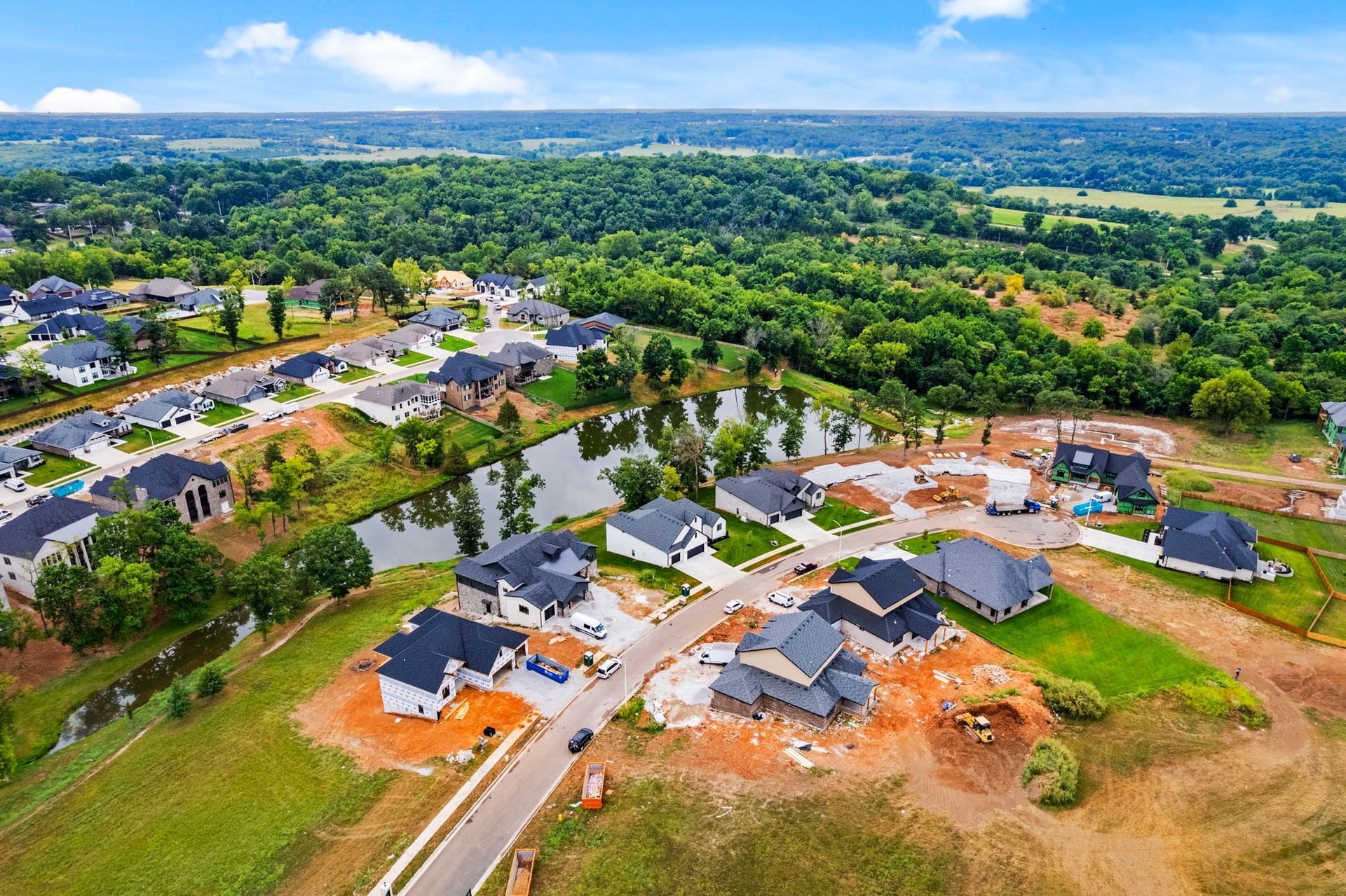 Aerial view of a cleared path through a grassy field, bordered by trees and a rural landscape under a blue sky.
