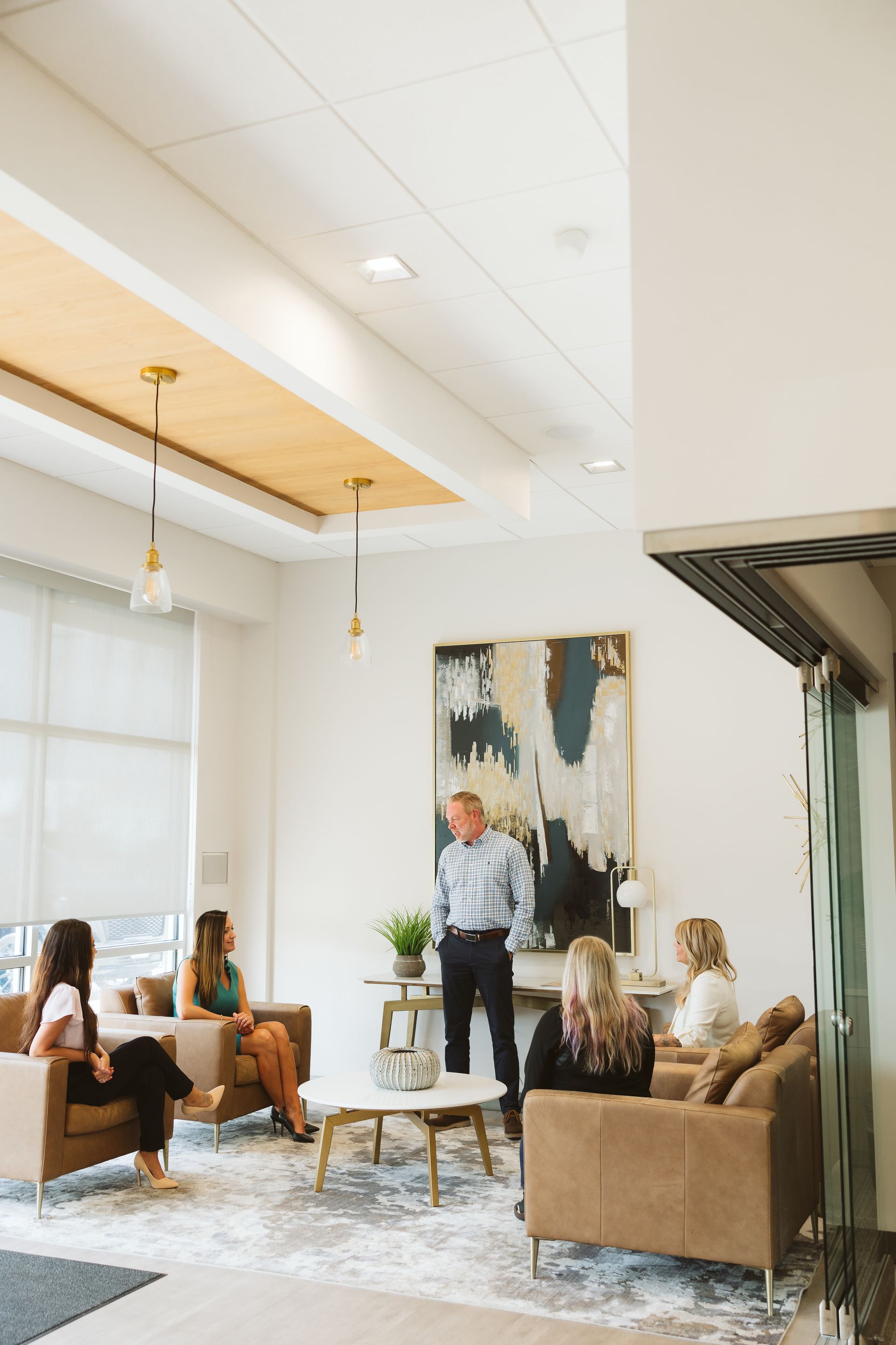 Aerial view of a suburban neighborhood with houses, pool, tennis courts, and surrounding trees. Blue sky.