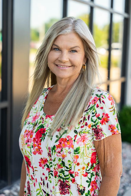 Bright kitchen with island, white cabinets, stainless steel appliances, and wooden flooring.