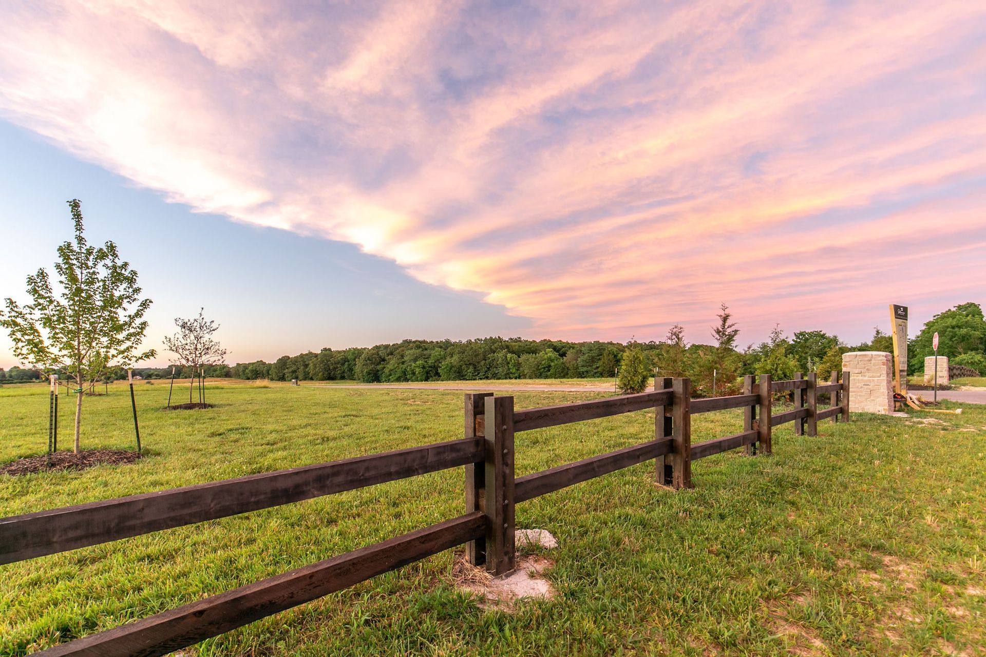 Aerial view of a residential area with houses, trees, and buildings under a blue sky.
