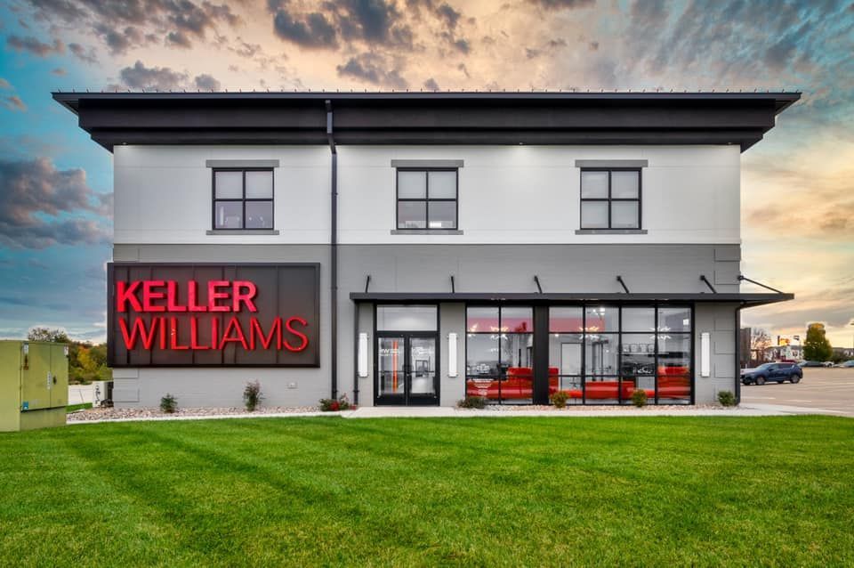 Keller Williams real estate office exterior with red signage and large windows at sunset