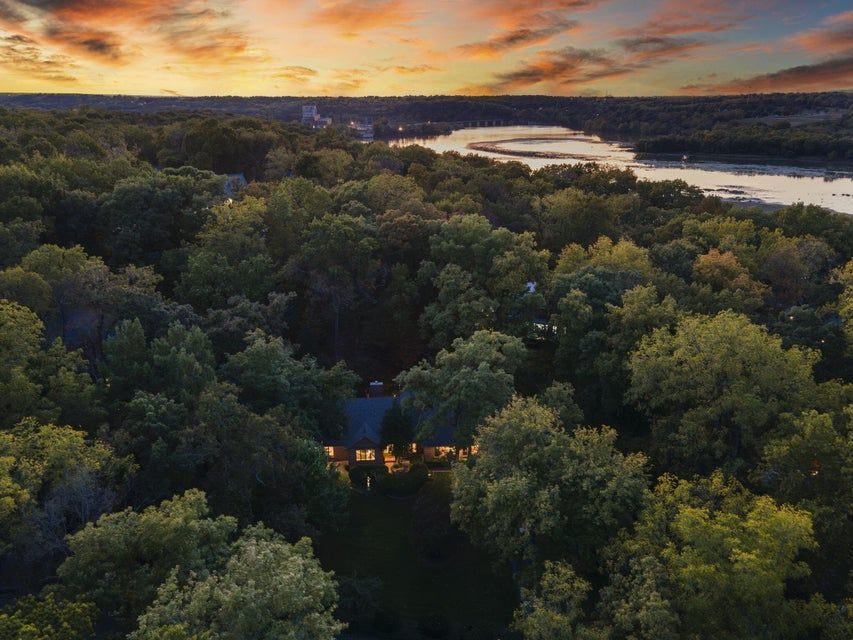 Aerial view of a suburban neighborhood with houses, green lawns, and curving streets, under a blue sky.